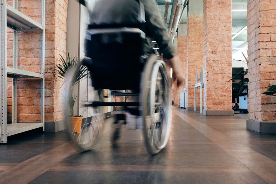 Person in a wheelchair moving down a bright office corridor